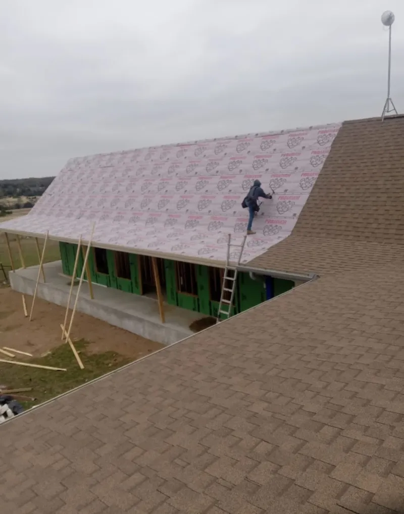 Worker preparing underlayment for a metal roof installation in Pineville